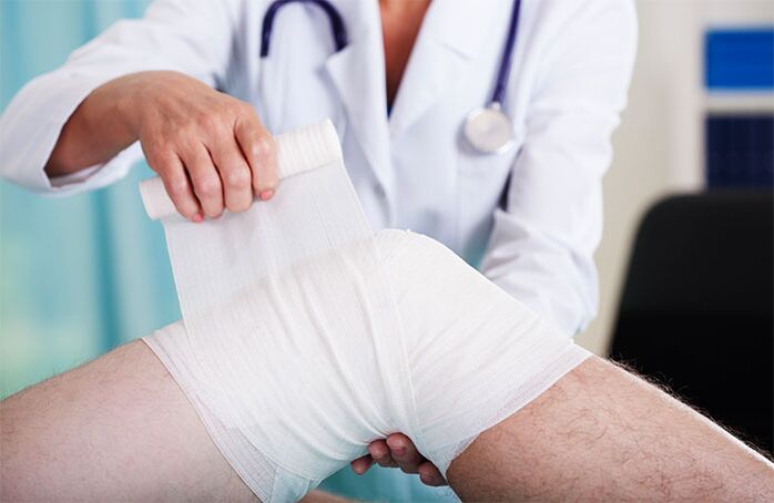mjeku që fashon nyjen e gjurit me artrozë
